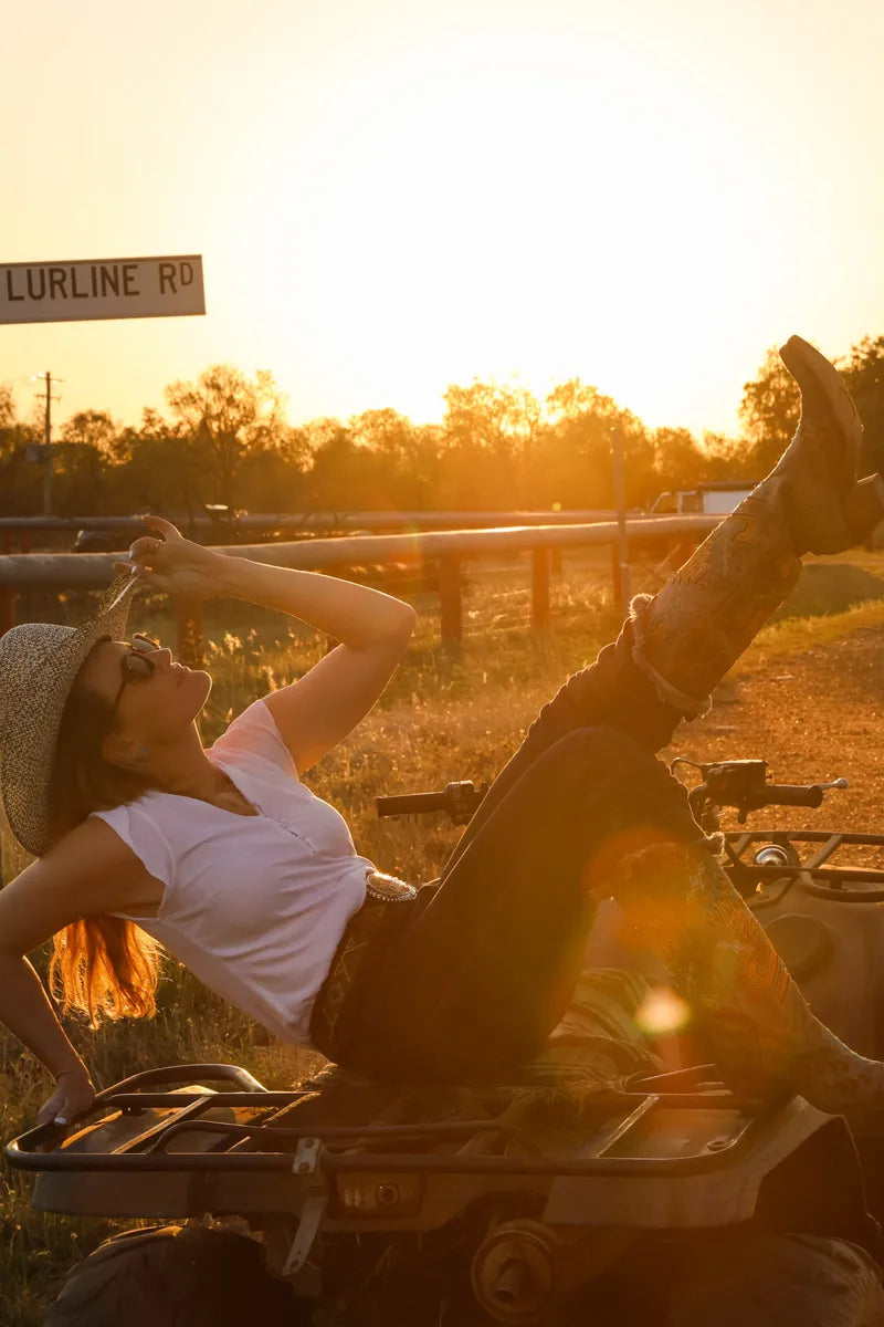 Woman relaxing on a four-wheeler at sunset in a rural setting